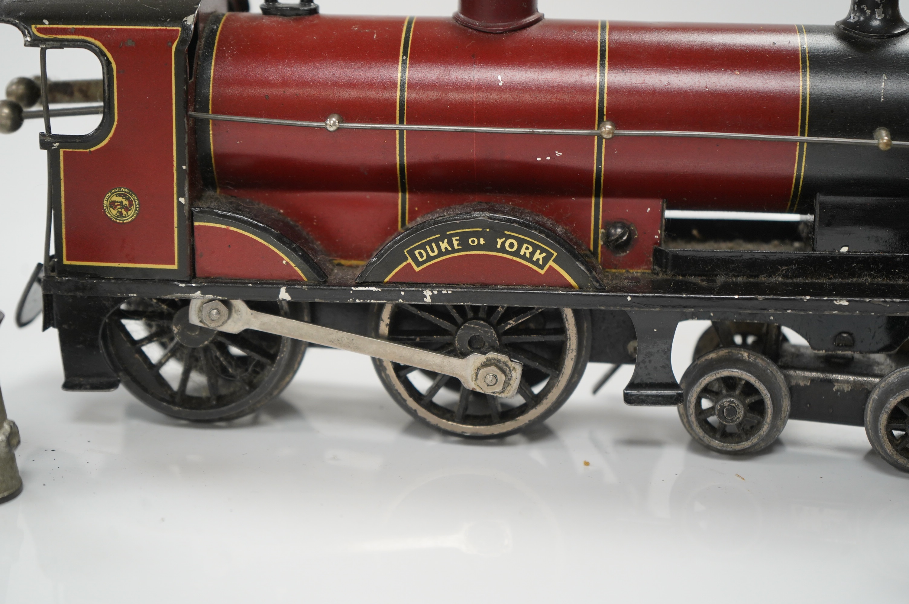 A Bassett Lowke O gauge tinplate clockwork 4-4-0 tender locomotive (missing tender), Duke of York, together with four Crescent/Britains lead railway figures and a milk churn. Condition poor to fair.